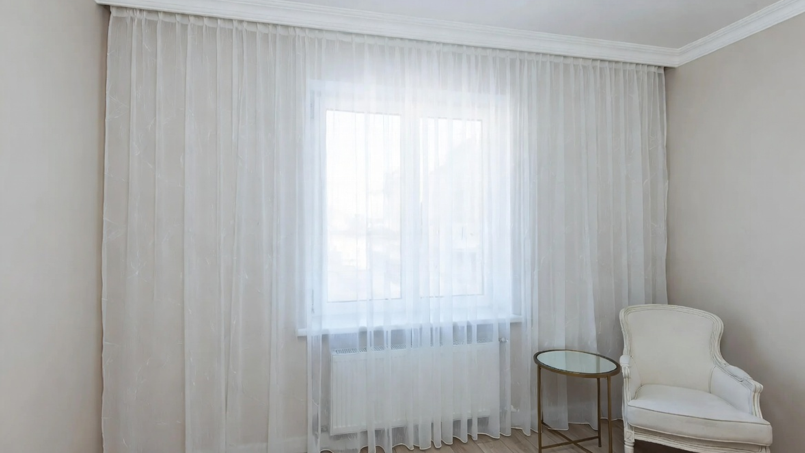 Custom curtains hung high and wide around a bright window to make the room feel taller and more open