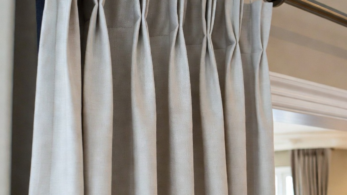 Heavy pleated curtains hung with sturdy hardware in a bright room, showing support for lined drapes