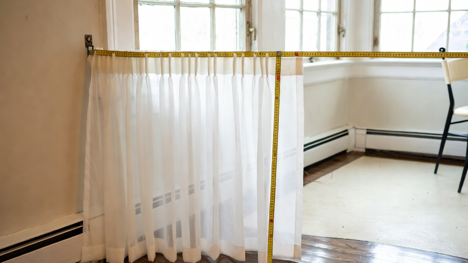Pinch pleat curtains measured and hung at a bright window with clear pleat detail and full-length drape
