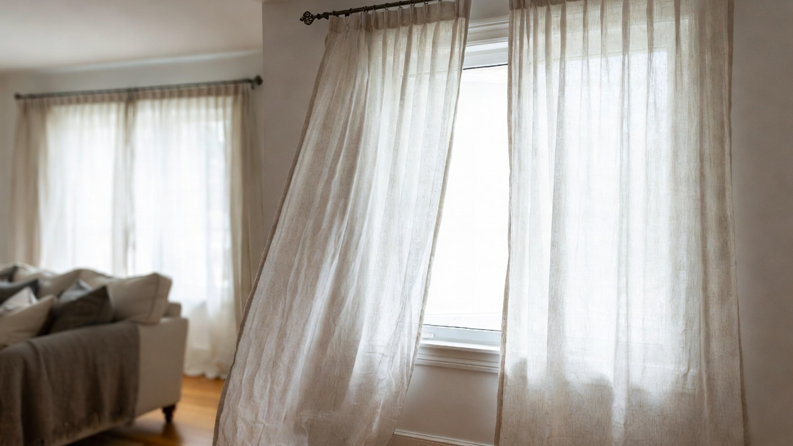 Belgian linen drapes in a bright living room with soft folds, natural light, and a refined relaxed look